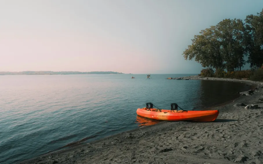 An orange kayak on the shore of a lake